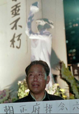 Плачещ хонконгски гражданин, държащ плакат с призив към хората да не забравят кървавата разправа на китайското правителство с протестиращите студенти през 1989 г.. 