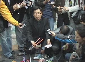 Свещеникът Джин Куи-Хо показва клещи, камъни и други предмети, които са били хвърляни по тях от китайските студенти. 