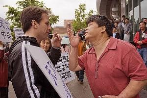 Про-комунистически поддръжник (вдясно) атакува словесно участник в кампанията за отказване от Китайската комунистическа партия.