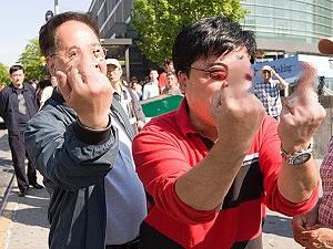 Поддръжници на Китайската комунистическа партия отправят неприлични жестове срещу практикуващите Фалун Гонг във Флашинг, Ню Йорк.