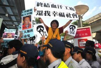Демонстранти развяват протестен банер, гласящ: "Спрете фабриките от кръв и пот, върнете щастливото общество" до портрет на Тери Гоу, директор на Foxconn