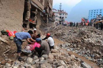 Оцелели жители покриват тялото на починал роднина, лежащ на импровизирана носилка сред развалините от свлачищното опустошение, докато спасителните операции на 11-ти август в област Джоучу (Zhouqu) в северозападната провинция Гансу (Gansu), Китай, продължават. 
