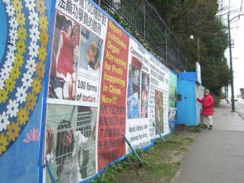 Практикуващ Фалун Гонг стои пред конструкции с постери, за които управата на Ванкувър твърди, че нарушават регулациите – твърдение, което не бе прието от Апелационния съд, донасяйки победа на Фалун Гонг в делото за поддържане присъствие пред китайското консулство във Ванкувър, с цел протести. Октомври 2010.