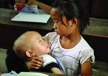 Ученичка от втори клас се грижи за малкото си братче по време на урок, тъй като няма на кой да го остави в къщи. Провинция Хунан