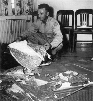 Майор Джес Марсел от военното летище в Розуел, с отломки, намерени на 120 км. северозападно от Розуел, САЩ, през юни 1947 г. Отломките са идентифицирани като части от радарна мишена.