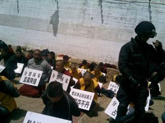 Тибетски монаси на колене, с вързани зад гърба ръце, с плакати около вратовете им, след като са били арестувани от китайските сили за сигурност. (От китайски военен форум)