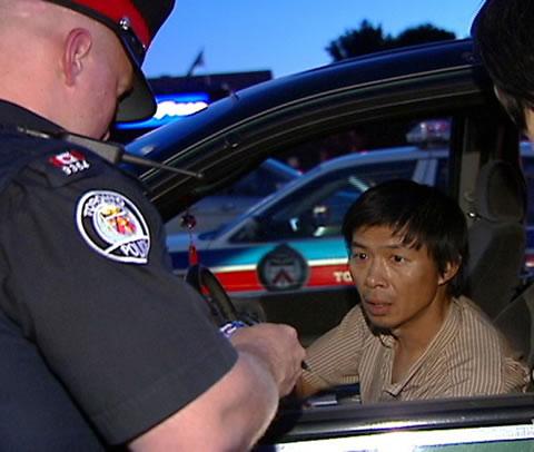 Полицията в Торонто разпитва Ли Пинг (Lu Ping) относно доставките на анти-Фалун Гонг таблоид през юни 2007 г. в азиатски магазин в Торонто, Канада. 