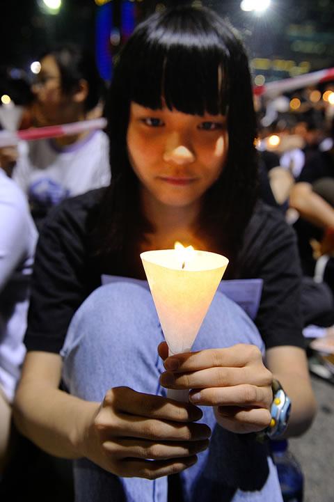 Момиче държи свещ в памет на жертвите на избиванията на площад "Тянанмън". 
