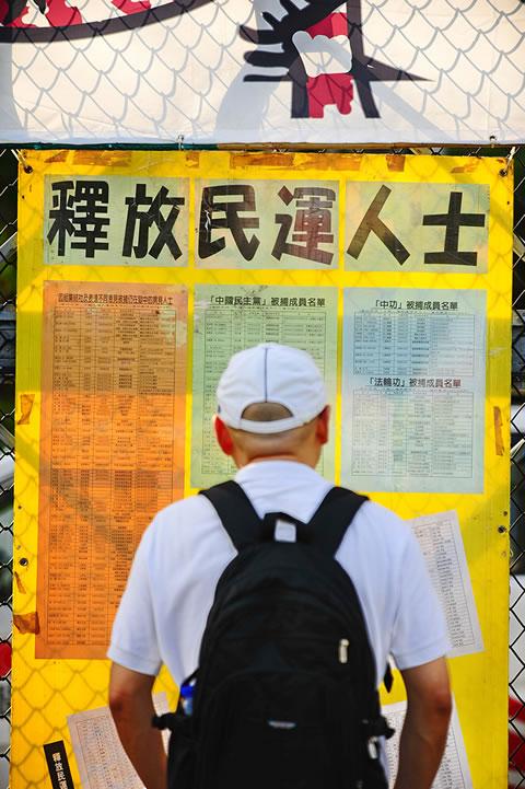 Мъж чете списъци на затворени дисиденти в Китай. Списъците включват членове на политически партии, различни от комунистическата партия, активисти за човешки права и практикуващи Фалун Гонг. 