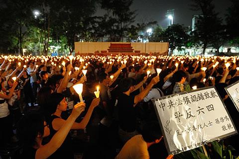Участниците в годишния мемориал държат свещи и плакати. Плакатът гласи: "Китайската комунистическа партия трябва да се извини и да реабилитира инцидента от 4 юни"