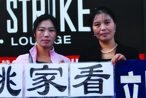 Ма Чуншя (вляво) и Ма Чунмей (вдясно) държат плакат с призив за помощ на сестра им по време на протест пред китайското консулство в Ню Йорк
